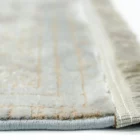 A close-up of a white and gold rug with a subtle, intricate design, made by Qaleen Carpets, showcasing their expertise in