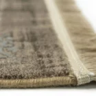 A close-up of a rug's edge, with a focus on the fringe and the soft, plush carpeting, made by Qaleen Carpets