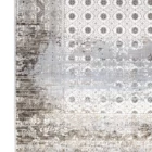 A close-up of a Qaleen Carpets rug with a distressed, vintage-inspired design, featuring a mix of neutral colors and a