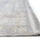 A close-up of a Qaleen Carpets rug with a soft, white, and gold pattern, featuring a delicate, intricate design