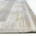 A close-up of a white and gold patterned rug with a fringe on one edge, made by Qaleen Carpets