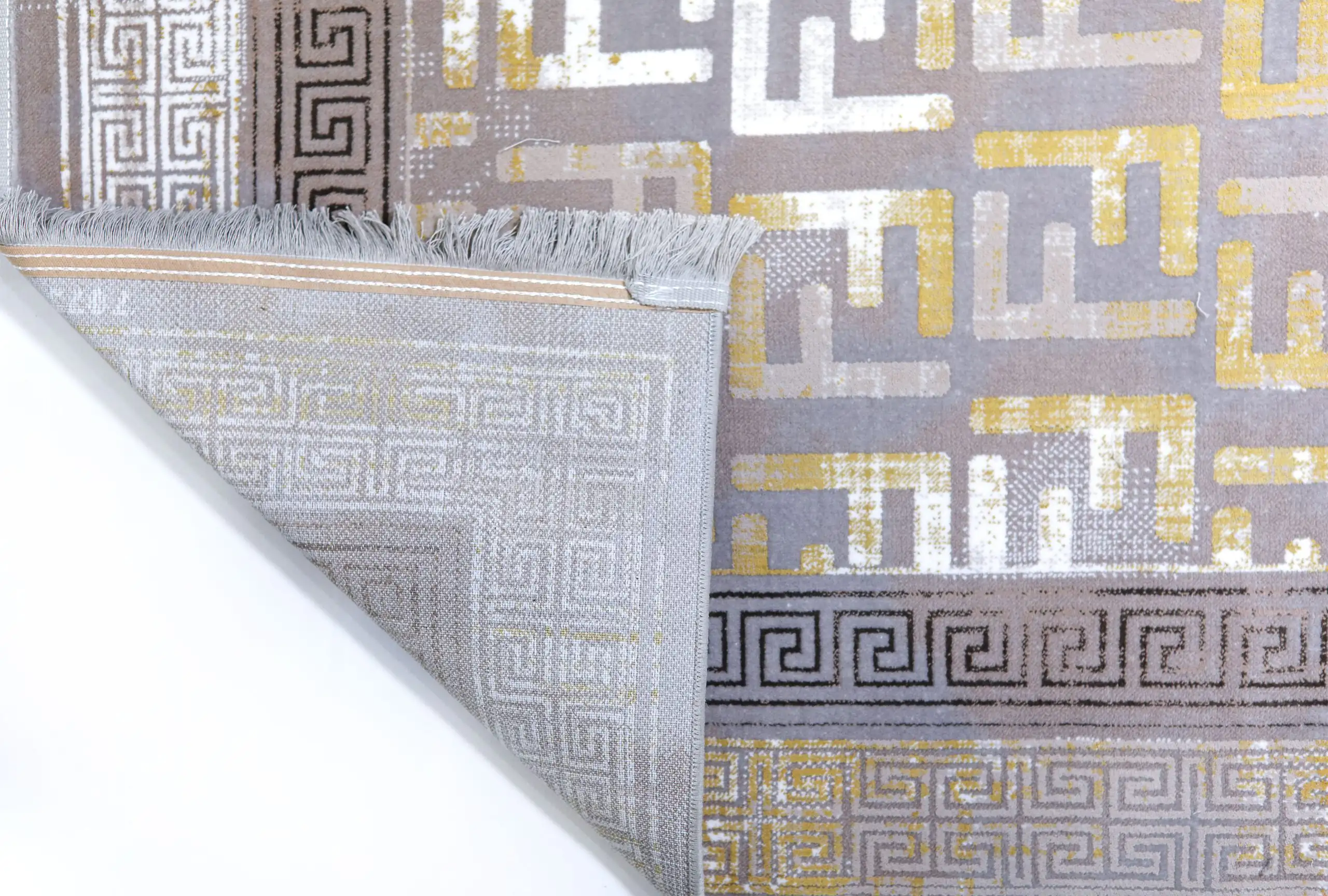 A close-up of a rug's corner, with a patterned design and frayed edges, made by Qaleen Carpets