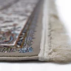 A close-up of a Qaleen Carpets rug with intricate patterns and a fringe on the edge, showcasing its high-quality
