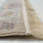 A close-up of a Qaleen Carpets rug's edge, with its intricate design and fringes on a white background