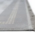 A close-up of a light grey and white striped rug with a subtle fringe on the edge, made by Qaleen Carpets