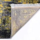 A close-up of a rug with a yellow, black, and grey pattern, with a white fringe at the edge, from the Qaleen Carpets