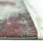 A close-up of a rug with a vibrant, intricate design, made by Qaleen Carpets, with a focus on the edge of the rug's fringe