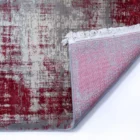 Qaleen Carpets A close-up of a rug with a red and grey pattern, with a corner folded over to show the underside, featuring a