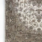 A close-up of a Qaleen Carpets rug with intricate, floral patterns in a neutral color palette