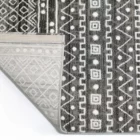 Qaleen Carpets A close-up of a rug with a patterned design, with the corner folded and the edge of the rug visible