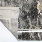 A close-up of a Qaleen Carpets rug with a unique, abstract design featuring a mix of dark and light colors, with a focus on