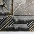 A close-up of a Qaleen Carpets rug, featuring a black and gold pattern with a white background