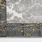 A close-up of a Qaleen Carpets rug with a geometric pattern, featuring a mix of black, white, and gold colors