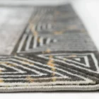 A close-up of a rug's edge, with a focus on the intricate pattern and the Qaleen Carpets brand