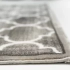 A close-up of a grey and white patterned rug with a thick, plush pile, made by Qaleen Carpets, with a focus on the rug's