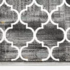 A close-up of a gray and white patterned rug with a Qaleen Carpets design, featuring a repeating pattern of interconnected