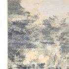 A close-up of a Qaleen Carpets rug with a unique, abstract design featuring a mix of blue, cream, and gold colors, with a