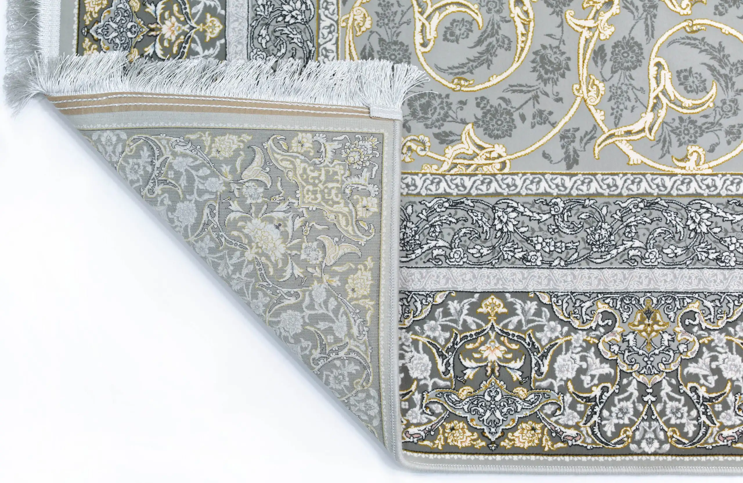 Qaleen Carpets A close-up of a gray and gold patterned rug with a fringe on the left side, against a white background
