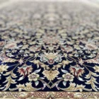 A beautiful, intricately designed carpet with a rich, dark blue background and intricate gold and red patterns, showcasing