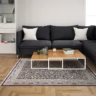 Carpets A living room with a dark grey couch, a coffee table, and a rug on the floor, featuring a mix of modern and