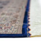 Qaleen Carpets' Persian-style rug features a cream-colored background with a blue border and intricate floral patterns in