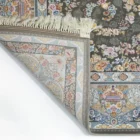 A Qaleen Carpets rug with a floral pattern and fringe, partially unrolled to show its design and quality