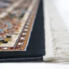 A close-up of a rug's edge, with a focus on its intricate design and Qaleen Carpets' quality