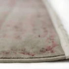 A close-up of a Qaleen Carpets rug with a subtle, intricate design and a soft, muted color palette, featuring a delicate