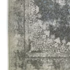 A close-up of a Qaleen Carpets rug with a distressed, vintage-inspired design in muted, earthy tones, featuring a central