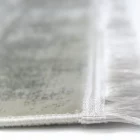 A close-up of a Qaleen Carpets rug's edge, with a focus on its fringe and weaved design