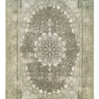 A Qaleen Carpets rug with a distressed, vintage-inspired design in muted green and cream tones, featuring a central