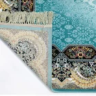 A close-up of a rug with a blue and white pattern, featuring a fringe at the top and a corner folded over to show the rug's