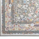A close-up of a Qaleen Carpets rug with a floral pattern and fringe on a white background