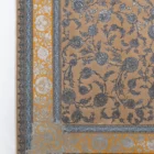 A close-up of a Qaleen Carpets rug with a floral pattern, featuring a mix of blue, gold, and white colors on a tan background