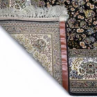 A Qaleen Carpets rug with a black background and intricate floral patterns, partially unrolled to reveal its intricate