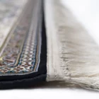 A close-up of a Qaleen Carpets rug with intricate patterns and a fringe, showcasing its high-quality design and craftsmanship