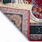 A Qaleen Carpets rug with a red, floral patterned design, partially unrolled to show its intricate details