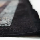 A close-up of a black and white rug with a fringe, made by Qaleen Carpets