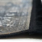 A close-up of a Qaleen Carpets rug with a fringe on a white surface, showcasing its intricate design and texture