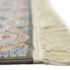 A close-up shot of a Qaleen Carpets rug, featuring a floral pattern on a gray background with a cream-colored fringe