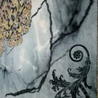 A close-up of a carpet with a floral pattern, featuring a mix of gold and black colors, with a focus on the intricate