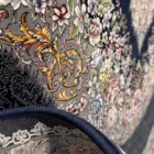 A close-up of a Qaleen Carpets rug with a floral pattern and a dark blue border, showcasing its intricate design and rich