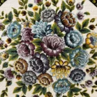 A beautiful, intricately designed carpet with a floral pattern, featuring a mix of colors and a central focus on flowers and