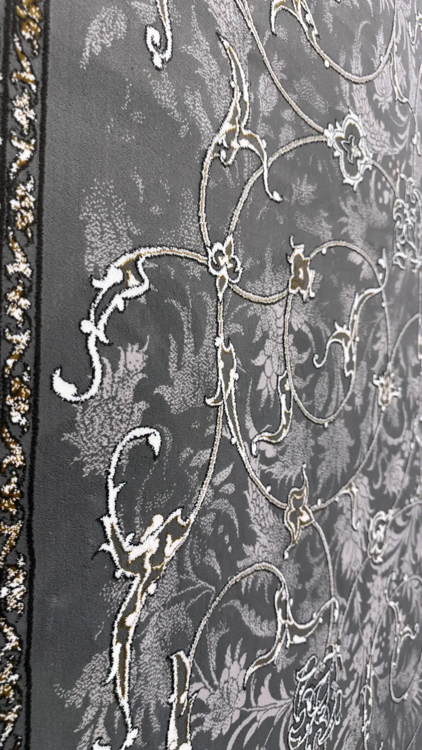 Carpets A close-up of a dark grey carpet with a floral pattern, featuring white and gold accents